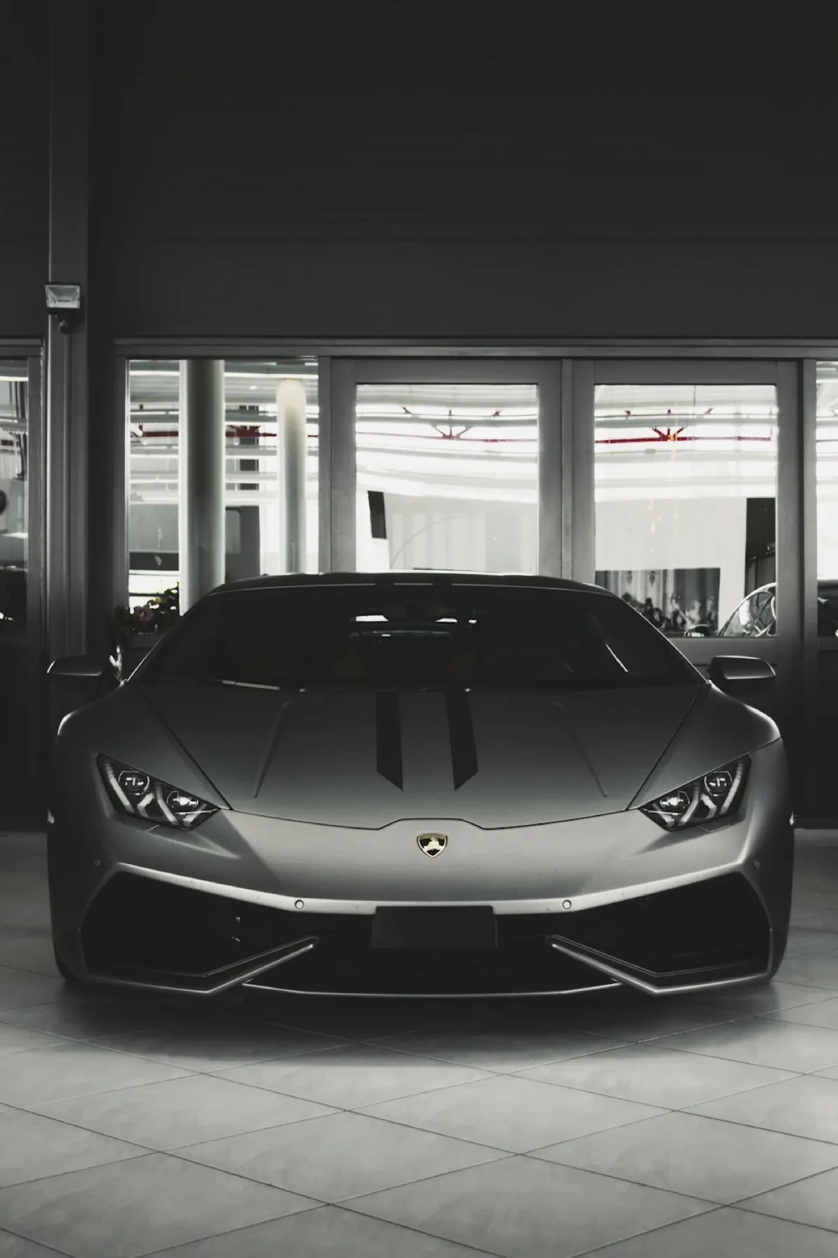 A matte grey Lamborghini Huracán front-on in a dark showroom