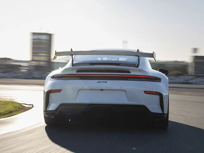 A white Porsche 911 GT3 seen from behind on a circuit