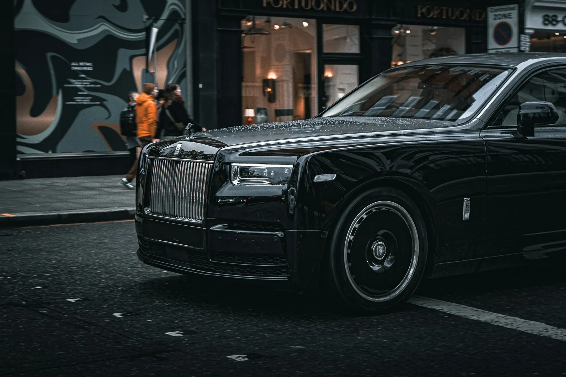 A black Rolls-Royce on a rain-soaked London street